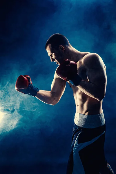 Siyah duman arka planında dövüşen sporcu kaslı boksörün yan görüntüsü. Boks sporu konsepti — Stok fotoğraf