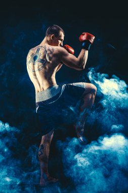 Diz vuruşu yapan Muay Thai savaşçısının tam boyutu duman arka planında izole edildi. karışık ortam 