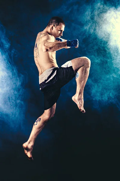 Tamaño completo de Muay Thai luchador que entrega de rodilla golpeó aislado en el fondo de humo. medios mixtos — Foto de Stock