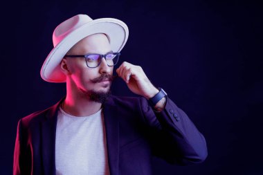 Modaya uygun bir adam. Stüdyo karanlık stüdyoda neon ışıkla çekiliyor. Ciddi bir adamın portresi.