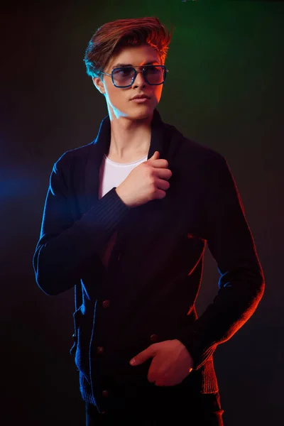 Neon licht portret van knappe man model met donker medium lengte haar, kapsel, dragen zonnebril — Stockfoto