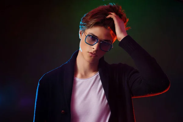 Neon light portrait of handsome male model with dark medium length hair, hairstyle, wear sunglasses — Stock Photo, Image