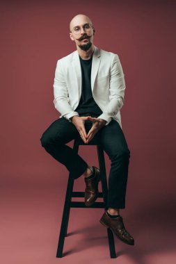 Kameraya bakarken sandalyede oturan genç bir iş adamının tüm vücudu.