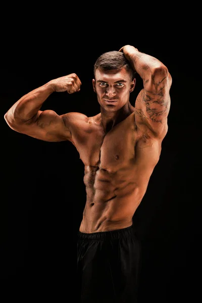 英俊有力的运动员满怀信心地向前看 强壮的健美运动员 完美的腹肌 二头肌 三头肌和胸部 背景是黑色的 — 图库照片