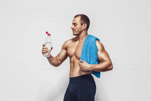 Muscular Man Holds Bottle Water While Wearing Sportswear Towel Isolated — Stockfoto