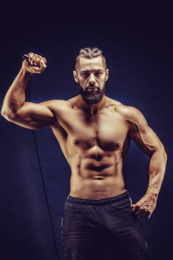 Kas yapan adam esneme bantlarını koyu arka planda esnetiyor.. 