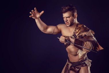 Portrait of handsome muscular gladiator with sword. Isolated. Studio shot. Dark background. 