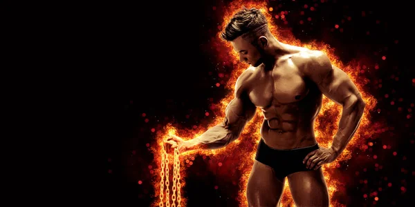 Body builder with fit torso belly chest and arms biceps triceps muscles holding chain while posing over the black background with fire. Bodybuilding concept.