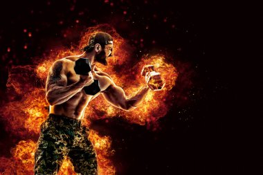 Handsome bearded shirtless tattooed bodybuilder workout wih dumbbell like boxer. Fire art concept. 