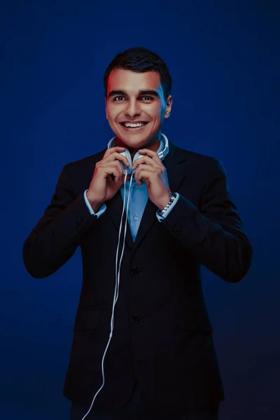 Portrait of smiling man with headphones on dark background. Studio shoot.