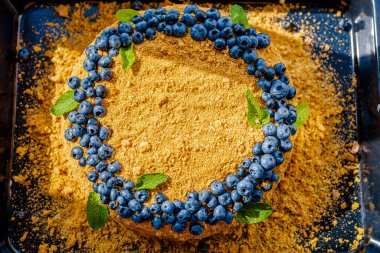 Homemade honey cake decorated with blueberry, top view.