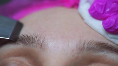 Güzellik uzmanı kozmetik uzmanı cihaz ile ultrasonik yüz temizleme, profesyonel kozmetik prosedürü bir güzellik kliniğinde müşteri için. Cilt bakımı ve makine kozmetoloji spa konsepti. 