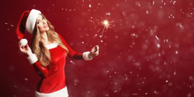 Çekici, şık sarışın elbise Noel holding yanan maytap ve sensually kameraya seyir için. 