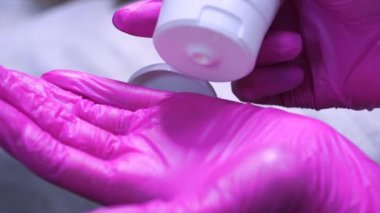 Yakın plan, pembe eldivenli eller şeker kutusundan beyaz kozmetik krem sıkar. Cilt bakımı. Kozmetoloji, güzellik salonu. İlaç. Yavaş çekim