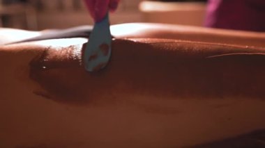 Kozmetik çikolata maskesi takan kadın. Kalçasında spa ameliyatı olan genç ve güzel bir kadın. Çikolatalı spa. Çikolata paketi.. 