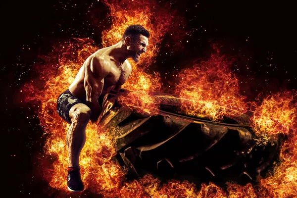 筋肉のフィットネスシャツのない男は炎の中で大規模なタイヤを移動 コンセプトリフティング トレーニングクロス — ストック写真
