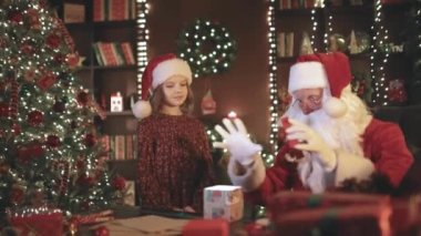 Noel Baba ve küçük asistan kız çocuklar için Noel hediyesi paketliyorlar. YILI YIL KONUŞMASI.