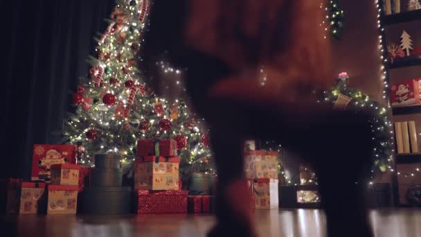 Klein Meisje Een Kerstman Hoed Sluipt Tenen Naar Kerstboom Draait — Stockvideo