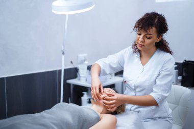 Spa Sağlık Kulübü 'nde yüz masajı yaptıran çekici bir kadın. Güzellik uzmanı lüks güzellik salonunda güzel bir bayanın yüz, boyun ve omuzlarına masaj yapıyor.. 