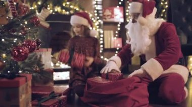 Noel Baba ve küçük kız yardımcısı Chek kimse görmeden Noel ağacının altına hediye kutuları koydular. Yeni yıl konsepti. Kamera hareket ediyor. 