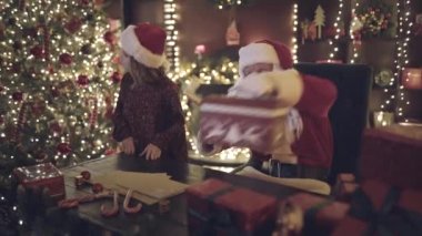 Noel Baba, küçük kız yardımcısının dikkatini dağıtmak için parmağını yana doğru uzatıyor ve sihirli hediyesini çıkarıyor. Kız Noel Baba 'yı şaşırttı ve kucakladı. Yeni yıl konsepti 