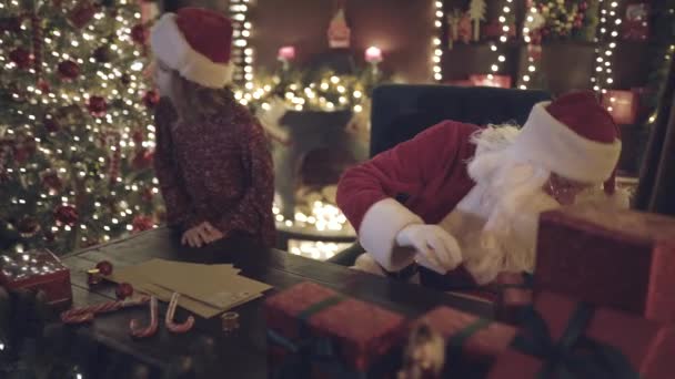 Kerstman Wijst Zijn Vinger Naar Zijkant Zijn Kleine Meisje Helper — Stockvideo