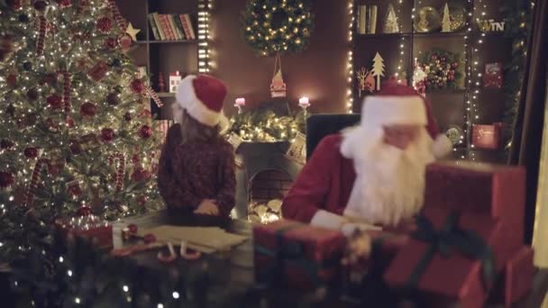 Kerstman Wijst Zijn Vinger Naar Zijkant Zijn Kleine Meisje Helper — Stockvideo