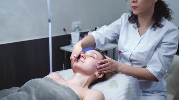 温泉健康俱乐部的迷人女性正在做面部按摩 美容师在豪华美容院为年轻漂亮女子按摩脸 — 图库视频影像