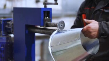 Boncuk makinesi. Teneke ürünler üretmek için atölyede çalışıyorum. Tanınmayan işçi, makinede metal levha yuvarlıyor. Ayrıntılar yakın. Teneke borunun oluşturulması.