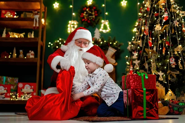Маленький Симпатичний Хлопчик Капелюсі Сантаса Виймає Подарунки Мішка Санта Клауса — стокове фото