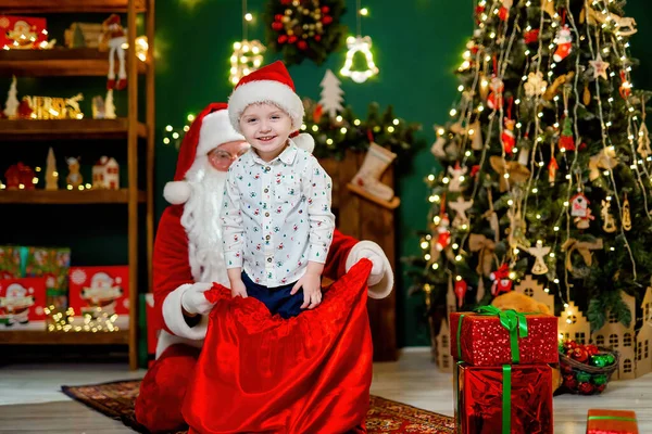 Щасливий Маленький Хлопчик Мило Розважається Сантою Клаус Граючи Мішком Подарунками — стокове фото