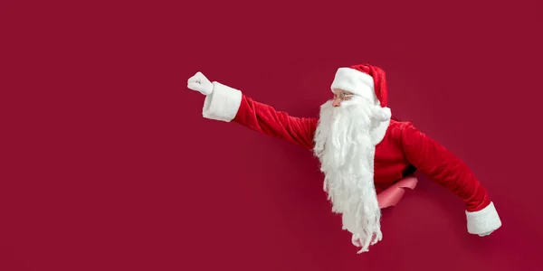 圣诞老人条款透过纸孔偷窥 同时像超人一样摆弄双手 圣诞节广告的概念 新年概念 — 图库照片