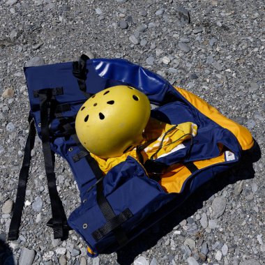 Sarı rafting miğferi taşlı bir nehir yatağında can yeleğinin üstünde..
