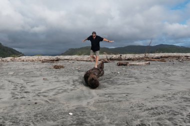 Sahilde sürüklenen bir kütük yaşlı bir adamın eğlenmesi ve dengesini test etmesi için bir platform sağlar.