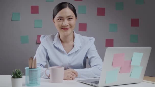 アジアの女性幸せな仕事でホームオフィス笑顔とカメラを見て — ストック動画