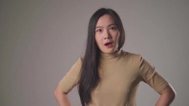 Kendine güvenen Asyalı kadın gülümseyerek ayakta duruyor ve arka planda tek başına kameraya bakıyor. 4K video.