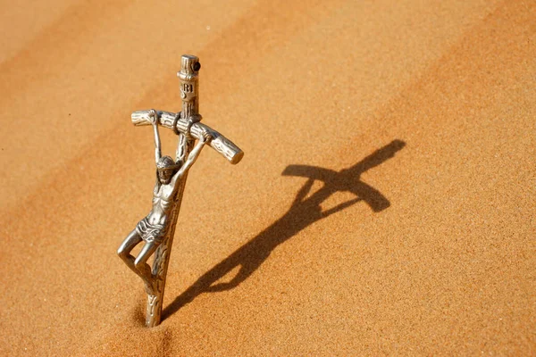 Crucifix on desert sand. Shadow of Jesus..