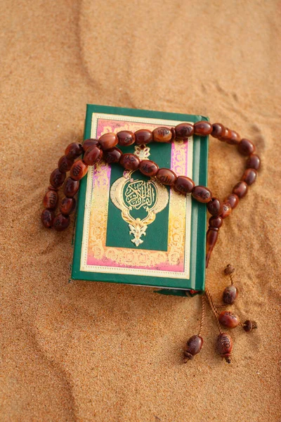 Coran and prayer beads in sand.  United Arab Emirates.