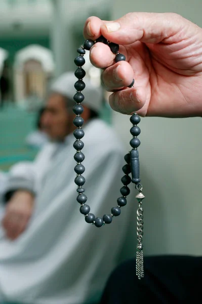 Muslim praying prayer beads in mosque.  France.