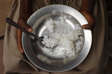 Pirinç yiyen Afrikalı kız. Okulda öğle yemeği. Togo.