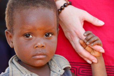 Afrikalı çocuk ve beyaz beyaz kadın arasında el ele tutuşmak. Yetim. Togo.