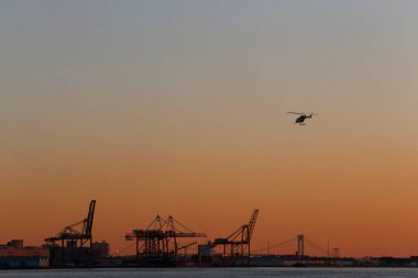 Helicopter and container cranes at sunset.  United states of America. 