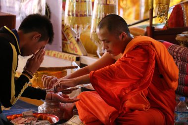 Wat Si Muang (Simuong) Budist tapınağı. Budist töreni. Keşiş bağları bir bileğin etrafına kutsanmış pamuk parantezi (Sai-sin) bağlar. Vientiane. Laos. 