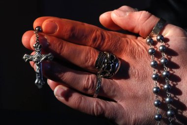 Kafatası yüzüklü bir adam tespih duası ediyor. Yakın plan. Fransa.