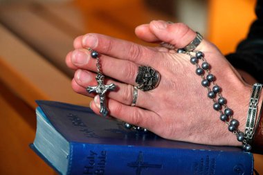 Kafatası yüzüklü bir adam tespih duası ediyor. Yakın plan. Fransa.