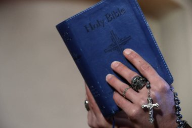 Kafatası yüzüklü bir adam tespih çekiyor ve İncil okuyor. Yakın plan. Fransa.