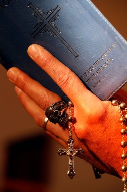 Kafatası yüzüklü bir adam tespih çekiyor ve İncil okuyor. Yakın plan. Fransa.