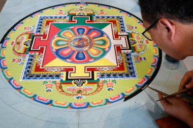 Kum mandala üzerinde çalışan Tibetli bir keşiş. Yakın plan.. 