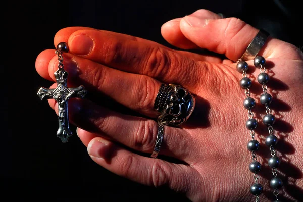 Kafatası yüzüklü bir adam tespih duası ediyor. Yakın plan. Fransa.