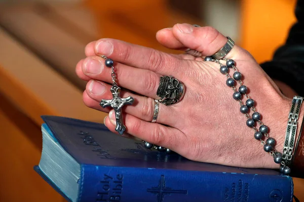 Kafatası yüzüklü bir adam tespih duası ediyor. Yakın plan. Fransa.